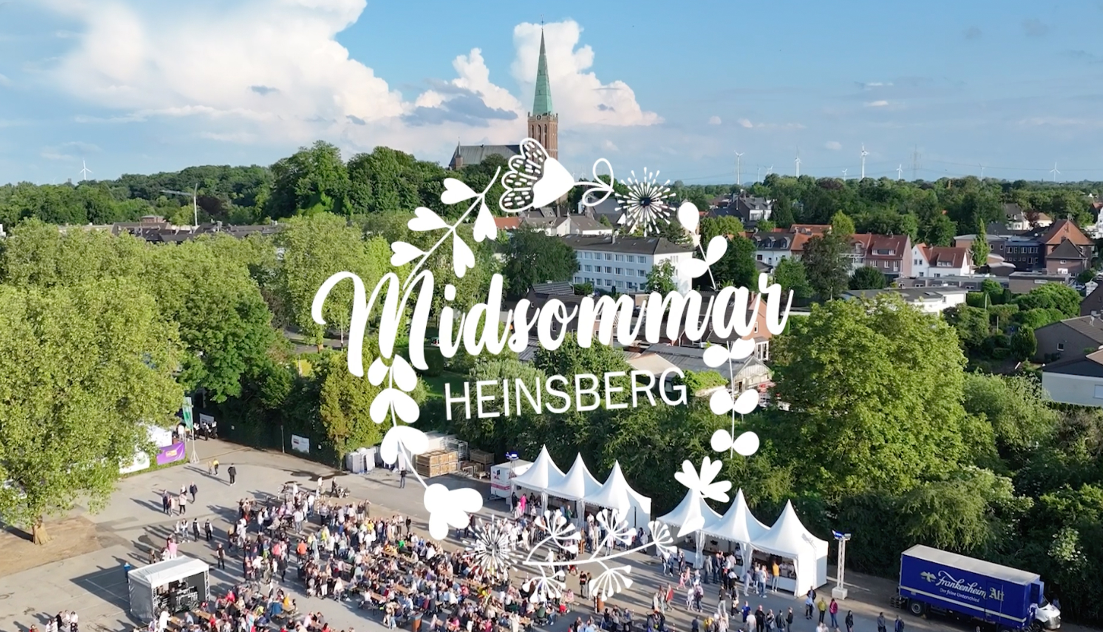 Blick aus der Luft auf tagsüber feiernde Menschen am Rande eines Parks